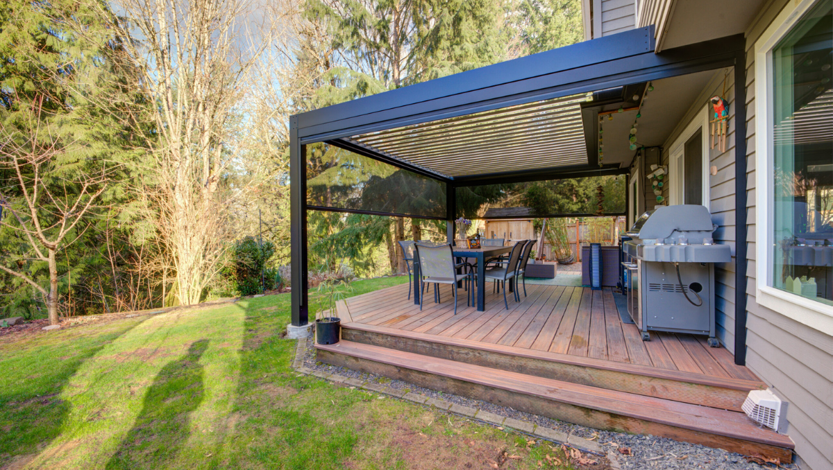 Modern black pergola installed over backyard deck with outdoor dining and grill area