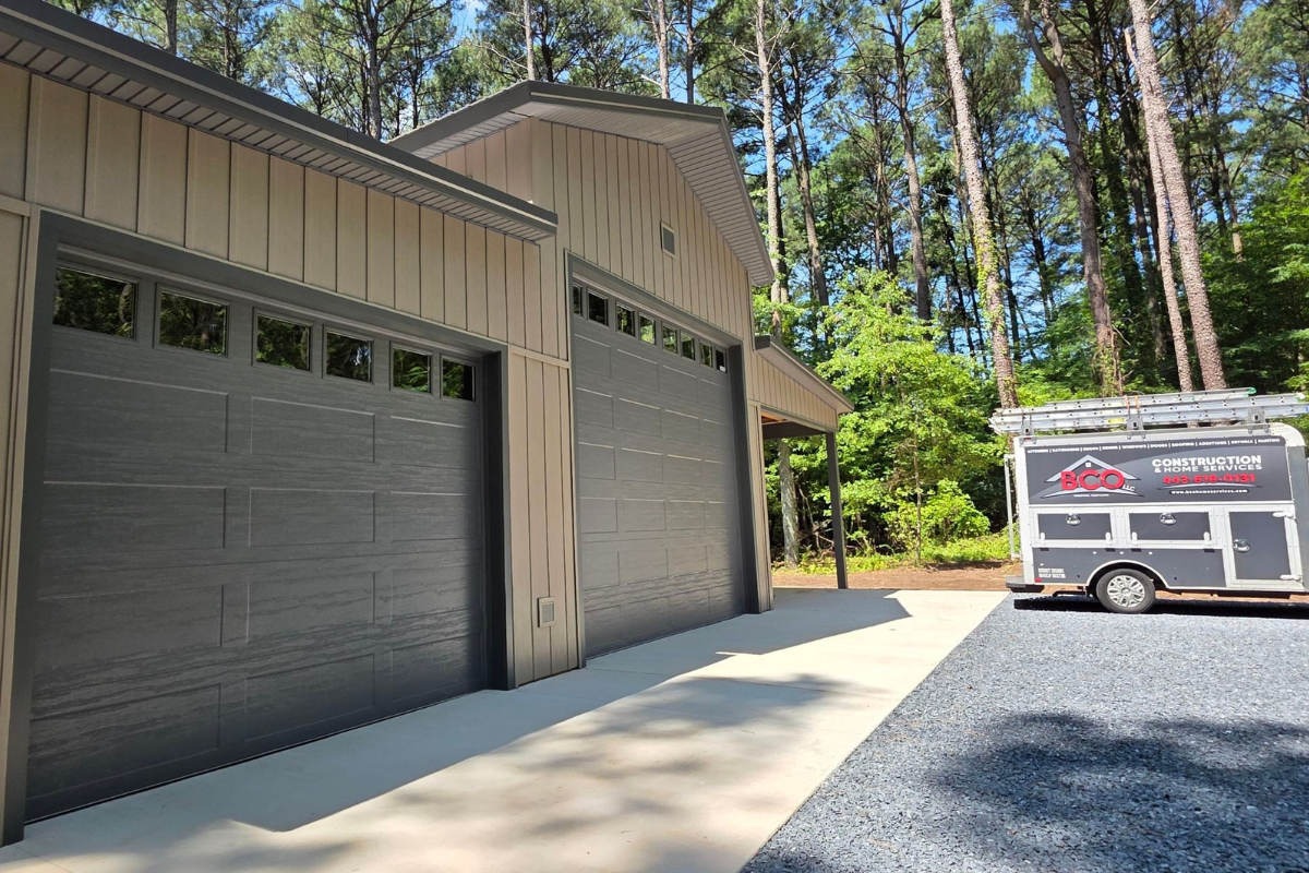 Side view of a completed custom pole barn with gray garage doors