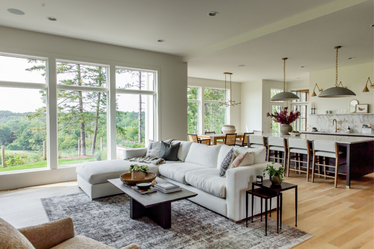 Bright living room with large windows overlooking a wooded landscape