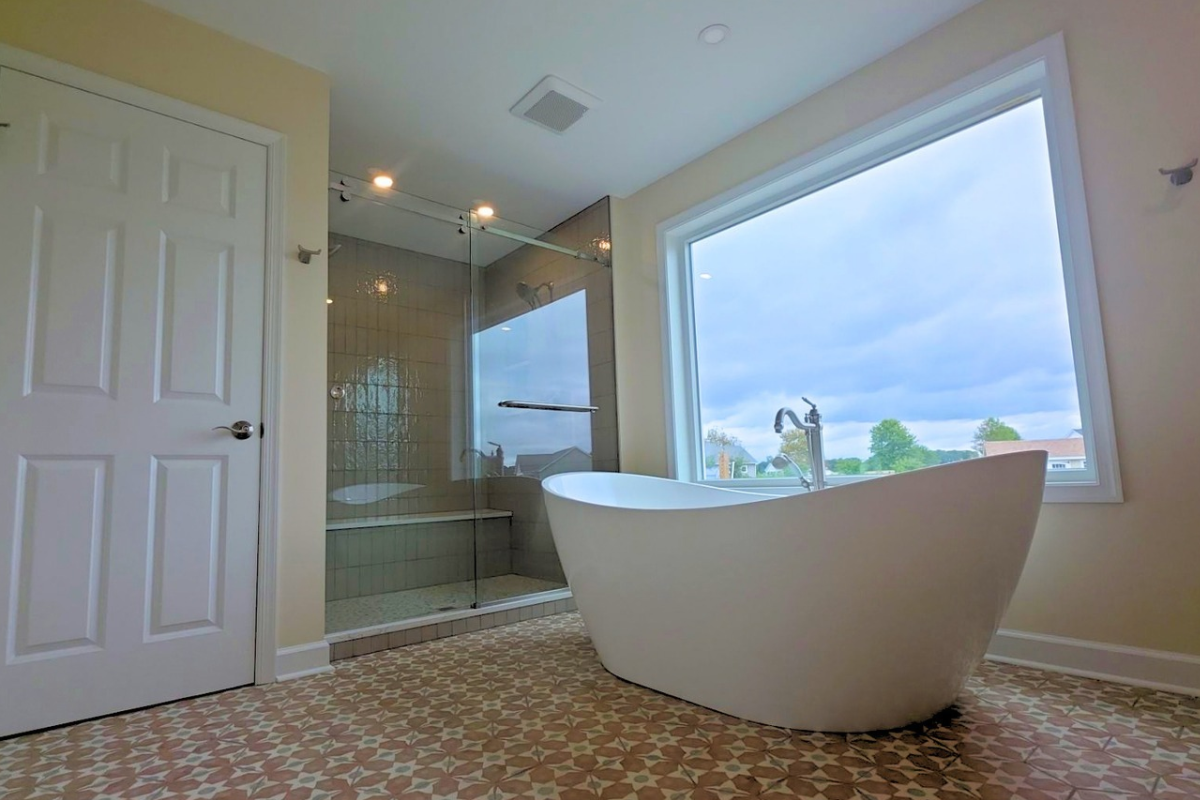 Luxury bathroom suite featuring a freestanding soaking tub beneath a large window