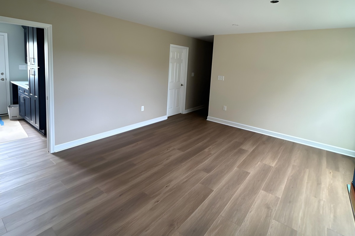 Garage conversion into a luxury bedroom suite with wood-look flooring and recessed lighting in Hurlock, MD